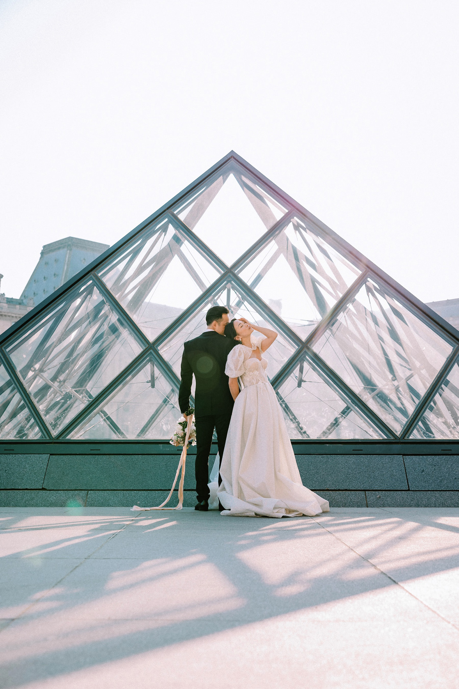 Couple posing in front of Louvre pyramid for Paris Editorial Photographer